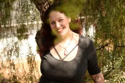 Katie Weatherup smiling brightly through branches of pepper tree