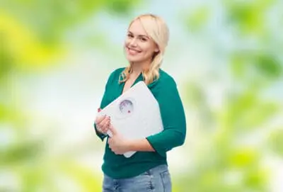 woman smiling and holding a scale demonstrating grace of shamanic weight loss