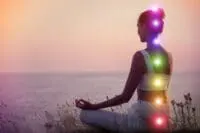 woman with chakras illuminated as she gazes at ocean. Soul retrieval supports your spiritual journey.