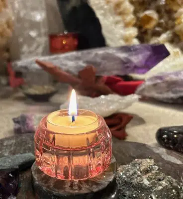 lighted candle in front of crystals symbolizing relief from spiritual attachments
